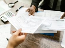 Hands exchanging financial documents, symbolizing the need for stricter disclosure of industry payments to doctors in medical education.