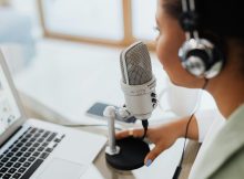 Podcaster with microphone and headphones recording content on a laptop, symbolizing the rise of decentralized media and community driven reporting.