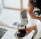 Podcaster with microphone and headphones recording content on a laptop, symbolizing the rise of decentralized media and community driven reporting.
