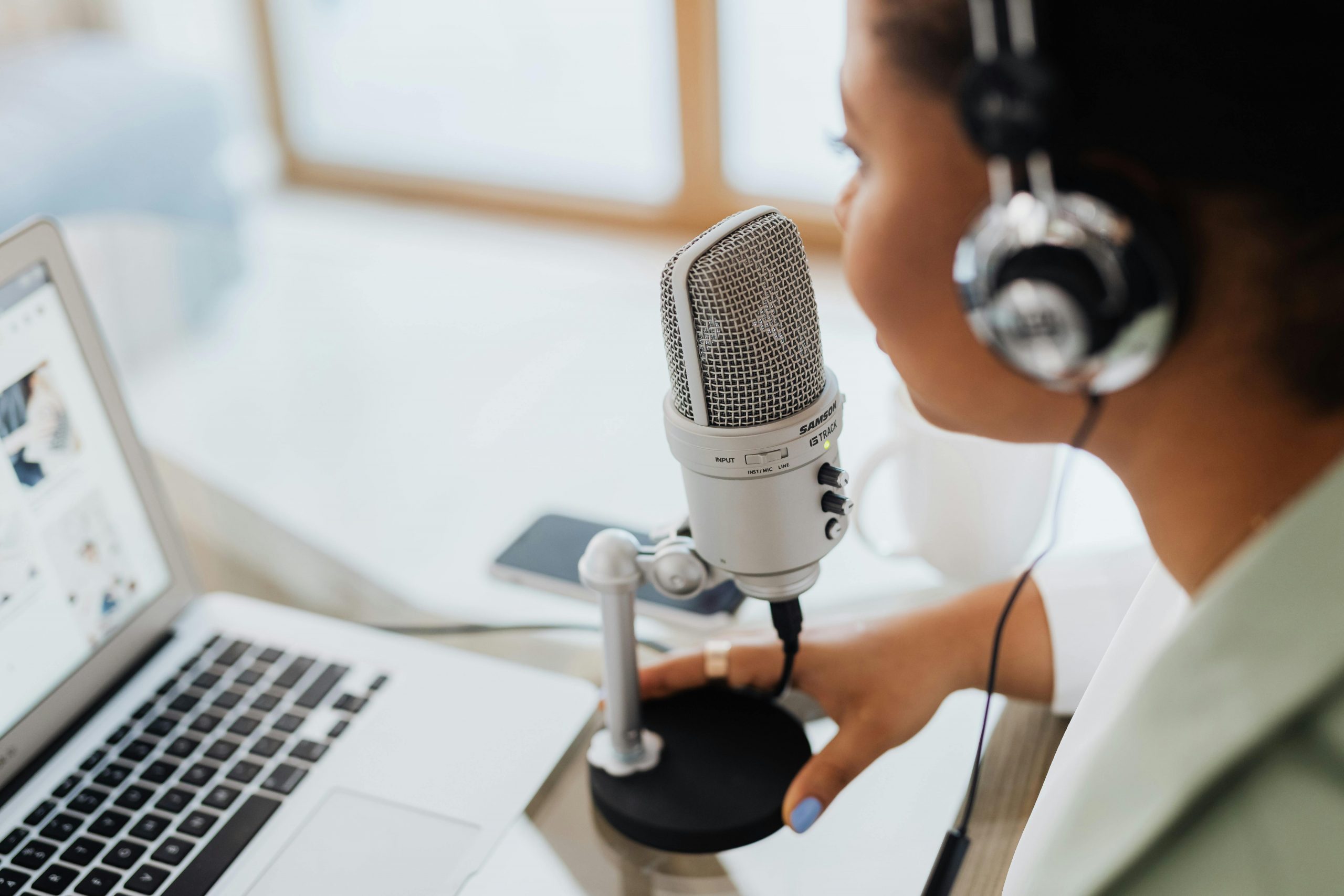 Podcaster with microphone and headphones recording content on a laptop, symbolizing the rise of decentralized media and community driven reporting.
