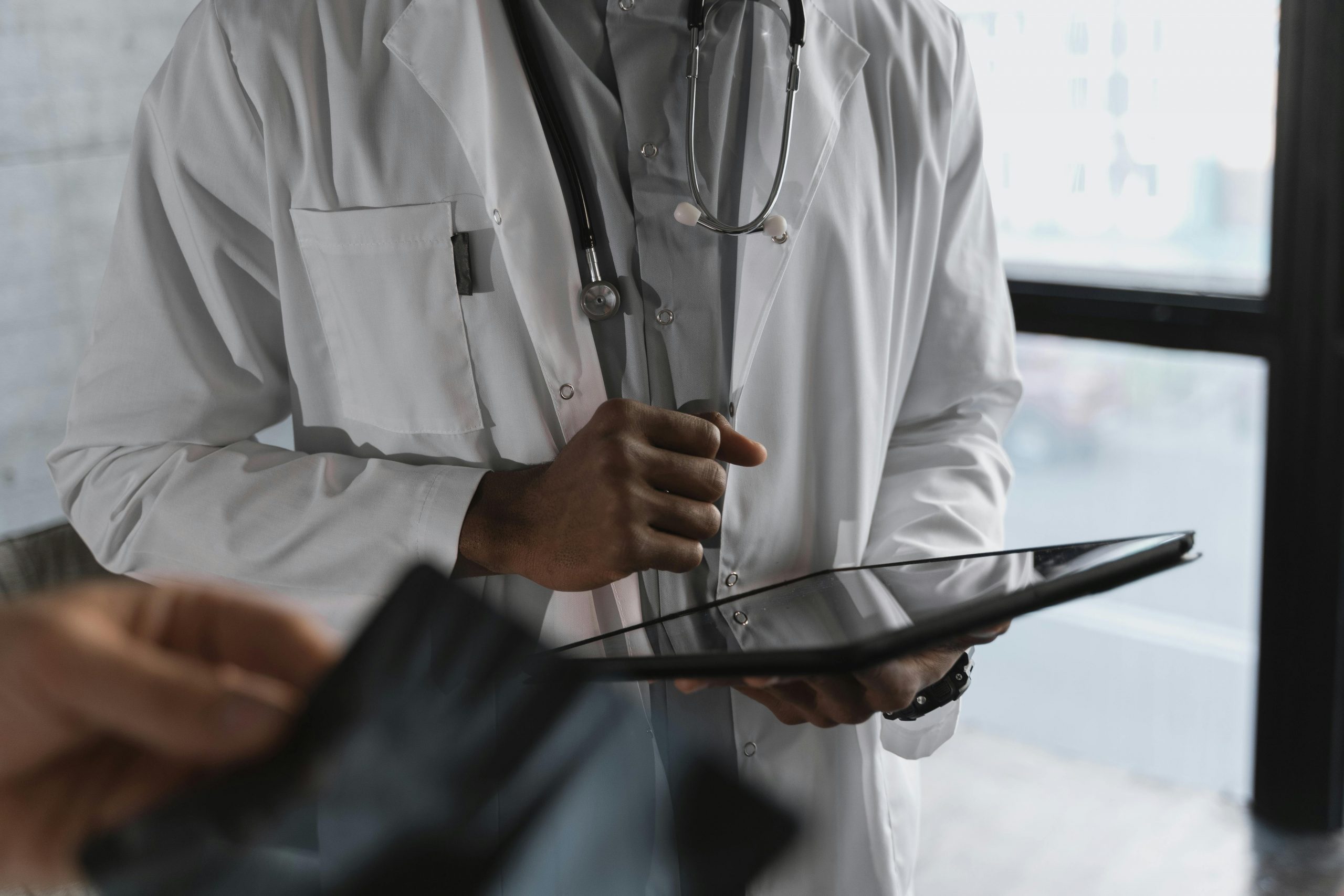 Doctor in white coat holding a tablet, symbolizing the need for affordable medical education and accessible healthcare in India.